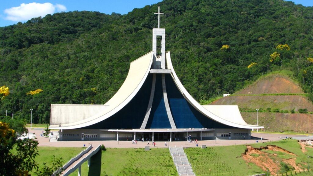 Dois grandes santuários e mais de 40 capelas e oratórios cercam um pequeno município onde trilhas atravessam Mata Atlântica, vinícolas preservam a herança italiana e um mirante a 525 metros permite enxergar até o mar