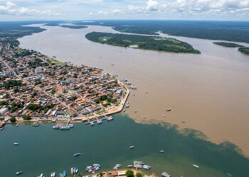 Vista do alto, uma cidade amazônica fica diante do encontro de dois rios de cores diferentes, onde as águas do Tapajós encontram as do Amazonas