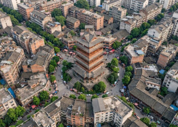 Vista do alto, uma cidade chinesa revela ruas inteiras convergindo para uma única torre vermelha no coração do centro antigo