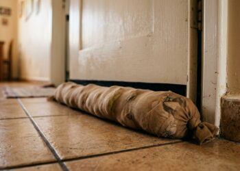 A gambiarra com uma meia-calça velha recheada de retalhos que vira uma barreira para bloquear a corrente de ar que passa por baixo da porta