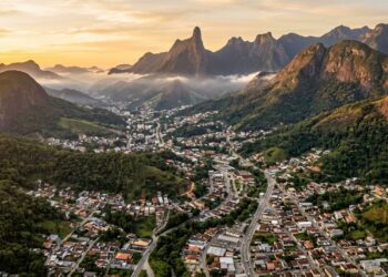 Teresópolis vista entre as montanhas cobertas pela Mata Atlântica, com o Dedo de Deus destacado na Serra dos Órgãos. - (Imagem gerada por inteligência artificial-ChatGPT/Olhar Digital)