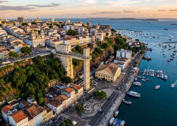Vista aérea de Salvador mostrando a Cidade Alta sobre a escarpa, a Cidade Baixa junto ao mar e o Elevador Lacerda conectando os dois níveis. - (Imagem gerada por inteligência artificial-ChatGPT/Olhar Digital)