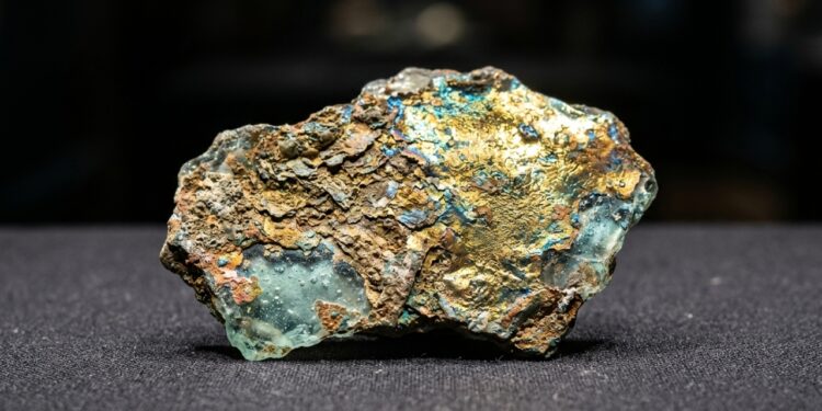 Fragmento de vidro romano de 2 mil anos com superfície dourada e iridescente formada pela corrosão ao longo dos séculos.