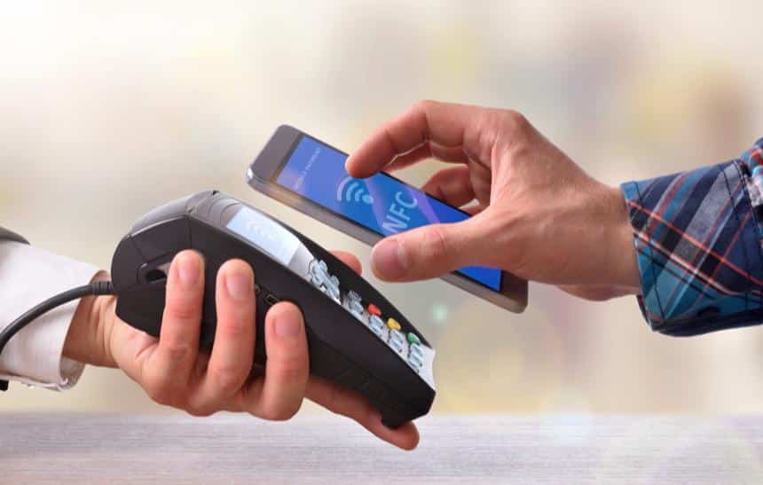 imagem de um homem realizando um pagamento aproximando o celular da máquina de cartão, representando um dos avanços dos meios de pagamento
