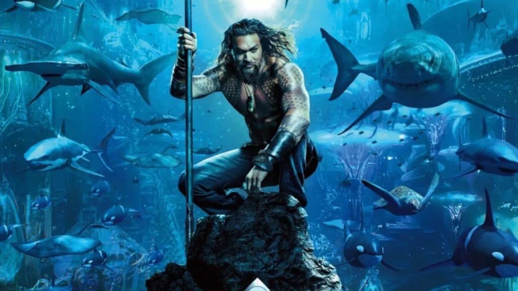 Imagem mostra pôster do filme "Aquaman", de 2018, com o ator Jason Momoa ao centro, segurando um tridente dourado enquanto é rodeado por vários animais marinhos