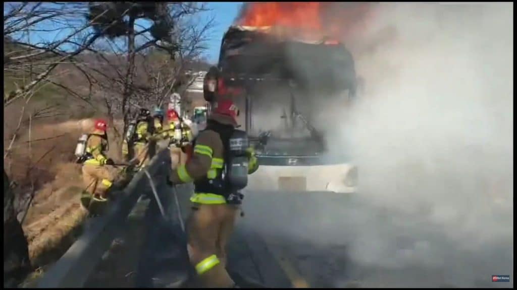 Imagem do ônibus elétrico da Hyundai incendiado, enquanto bombeiros tentam controlar as chamas