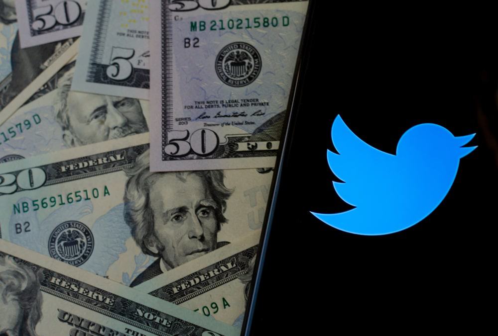 Twitter logo on the smartphone screen and US dollar bills