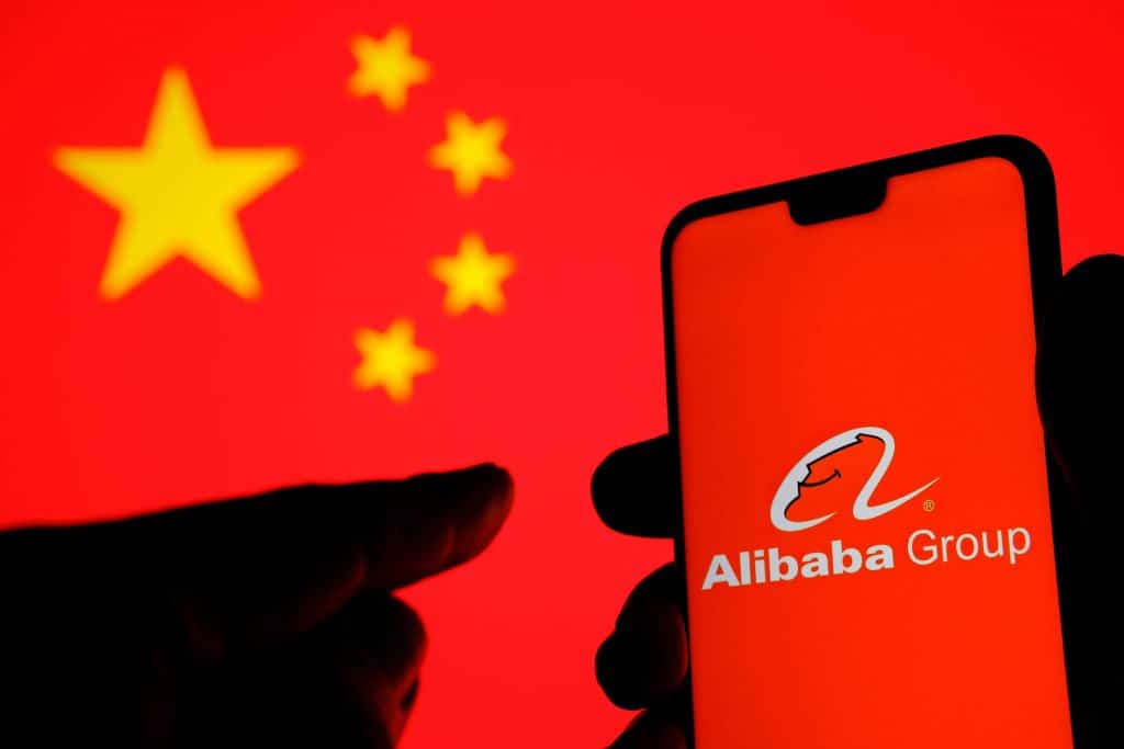 Logo do grupo Alibaba em um smartphone com uma bandeira da China ao fundo