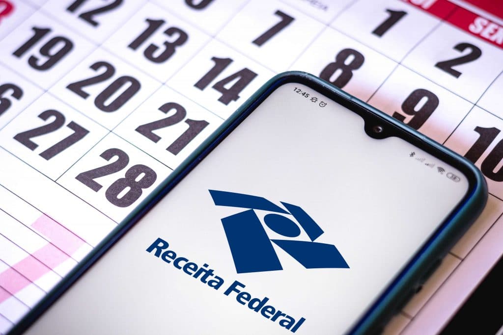 Celular com a logo da Receita Federal em cima de um calendário