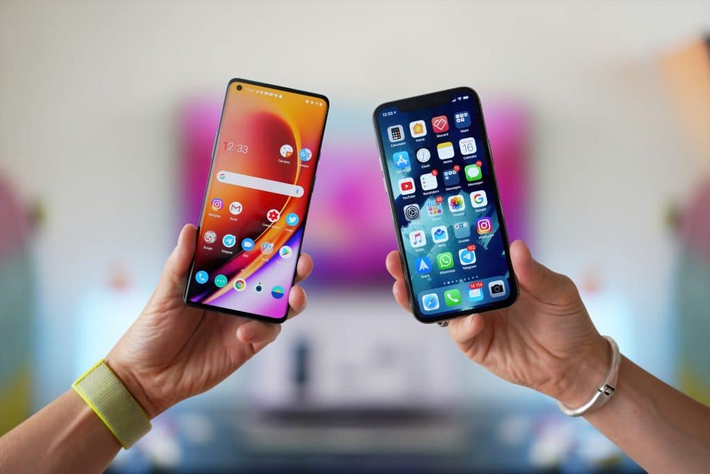 Mãos segurando dois smartphones lado a lado, um iPhone e um Android