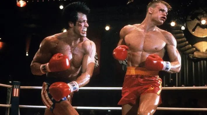 Cena do filme "Rocky IV", onde Rocky Balboa, vivido por Sylvester Stallone, acerta um soco no rosto do oponente Ivan Drago, vivido por Dolph Lundgren, em uma luta profissional de boxe