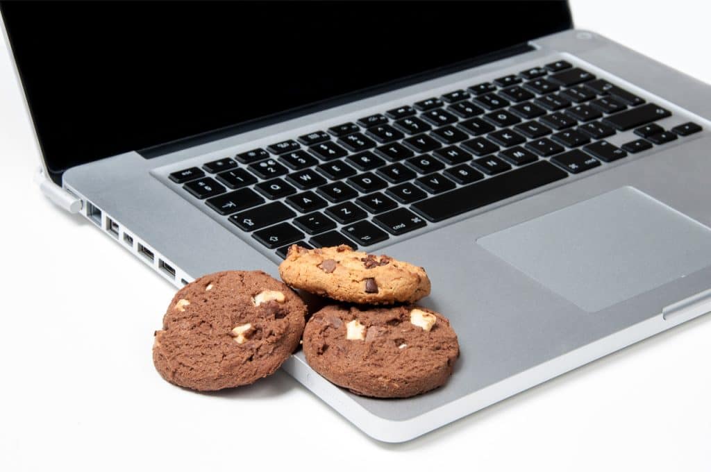 Imagem de alguns biscoitos posicioados sobre um computador, representando os "cookies de internet"