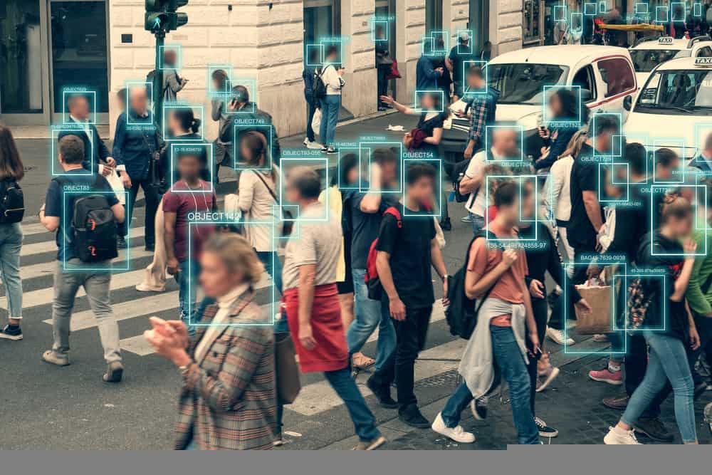 Rua cheia de pedestres, com um quadradinho verde em cima de cada rosto, indicando que há uma tecnologia de reconhecimento facial atuando no cenário