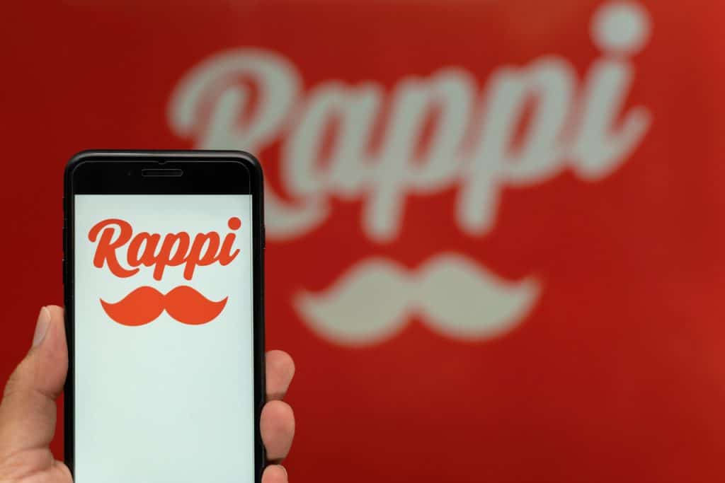 Amazon compra participação na Rappi com aporte inicial de US$ 25 milhões A Amazon comprou uma parcela da Rappi. Segundo a Bloomberg, a empresa de Jeff Bezos acaba de investir US$ 25 milhões na startup colombiana de delivery avaliada em mais de US$ 5 bilhões, em movimento estratégico na América Latina. O aporte garante à Amazon até 12% do capital da Rappi no futuro, de acordo com metas estipuladas. Logo do Rappi em smartphone