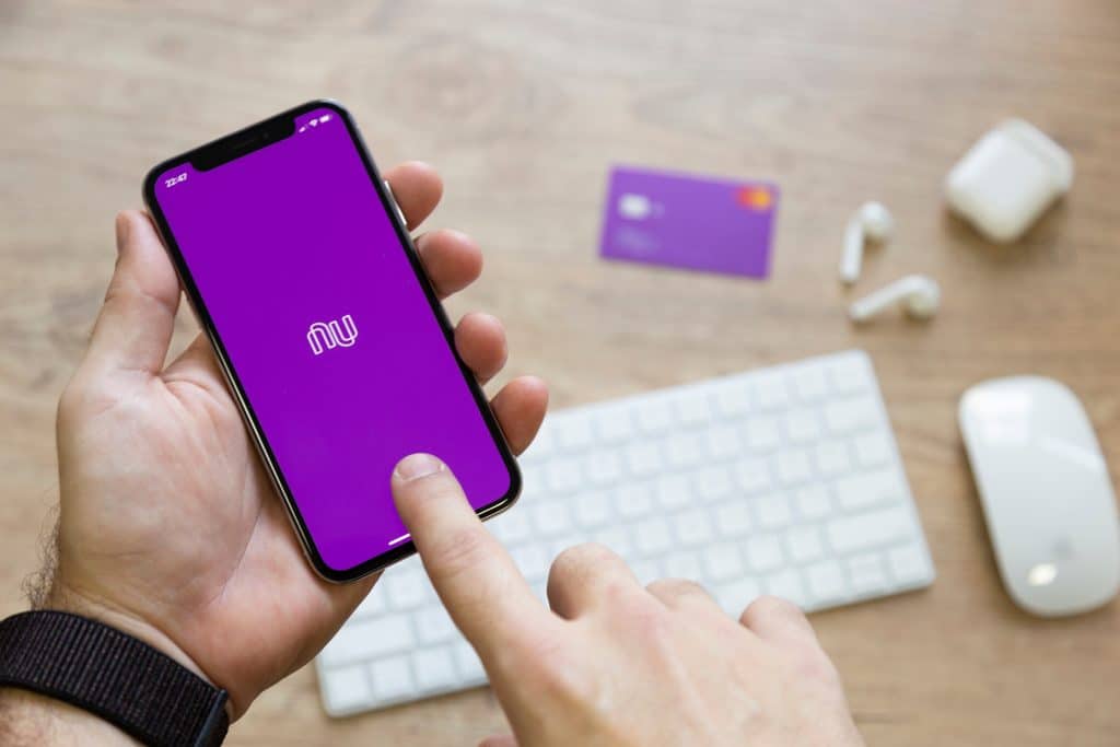 Um par de mãos segura celular com app do Nubank aberto