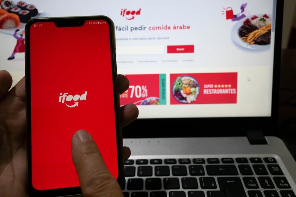 Logo do iFood na tela de um celular e computador