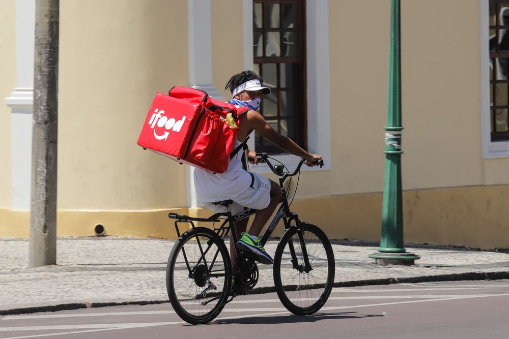 Homem de bicicleta com uma mochila térmica do iFood