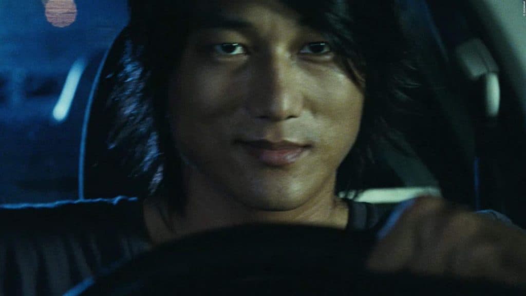Han (Sung Kang) segurando o volante em cena de Velozes e Furiosos: desafio em Tóquio