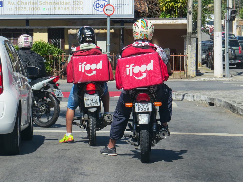 Dois motoboys com mochilas doiFood