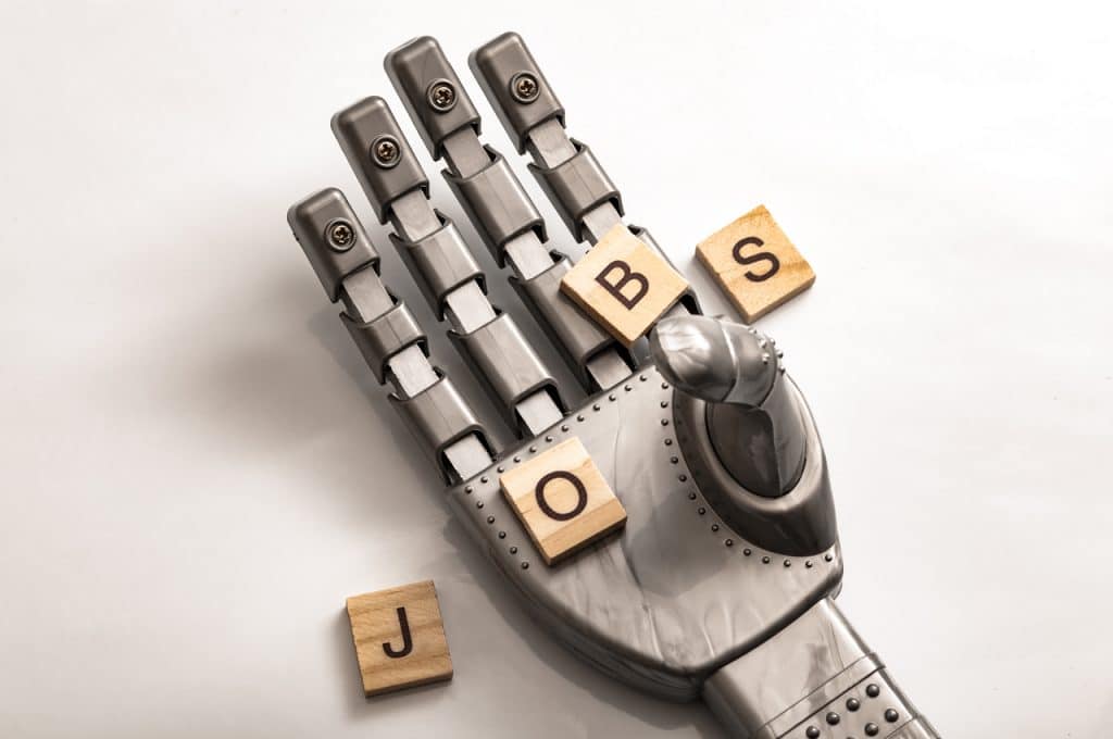 Ilustração de automação, com mão robótica segurando a palavra "jobs" (empregos, traduzido para o português)