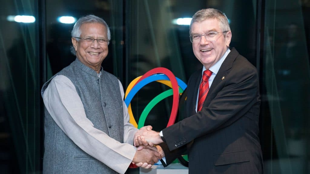 Imagem mostra Muhammad Yunus cumprimentando o presidente do Comitê Olímpico Internacional, Thomas Bach, durante cerimônia realizada em 2020