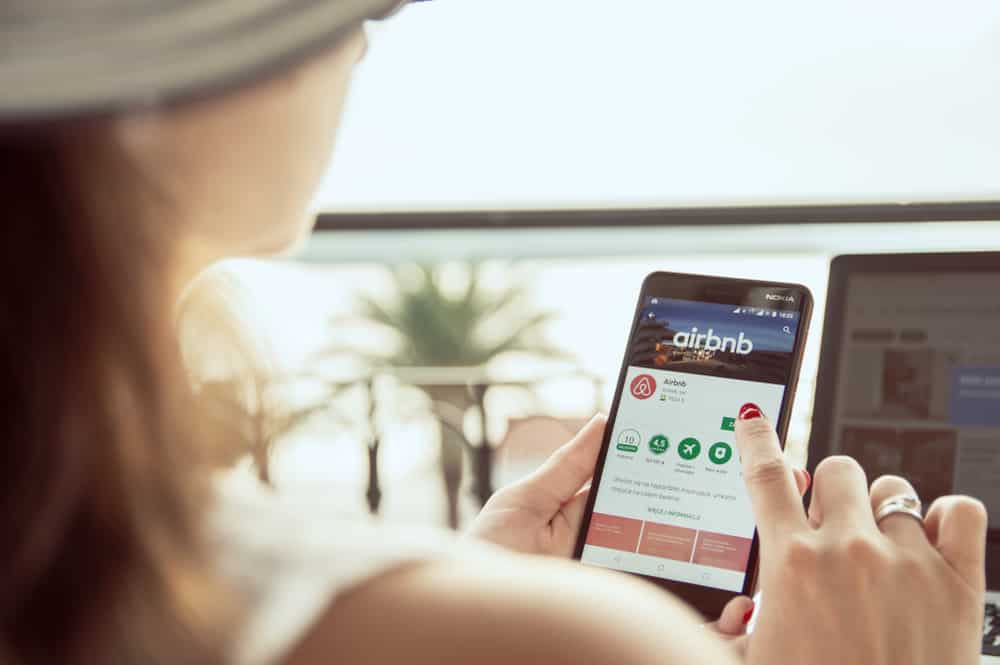 Mulher mexendo no aplicativo do Airbnb