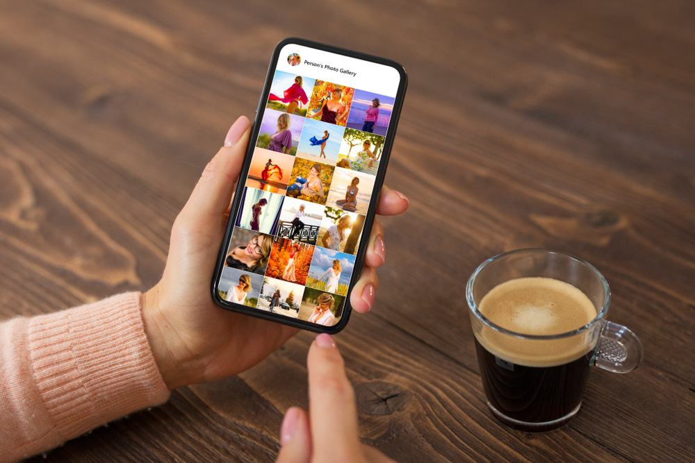 Celular aberto na galeria de fotos com uma xícara de café do lado