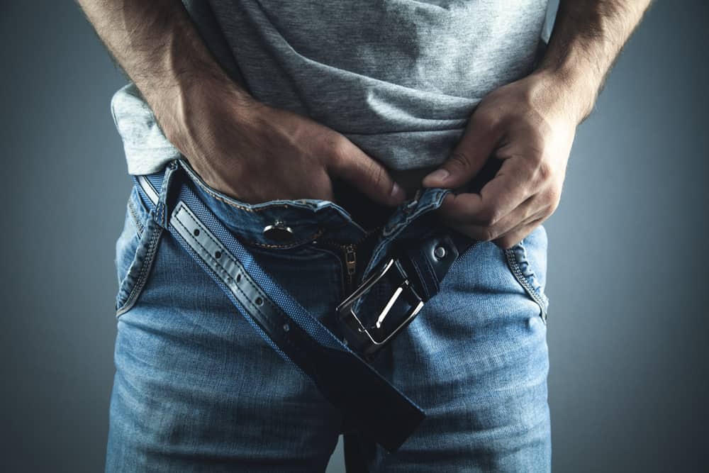 Homem com as mãos dentro das calças 