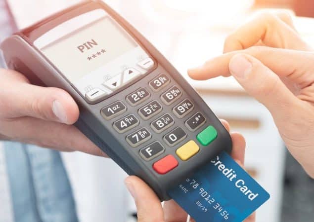 Consumidor pagando uma compra com cartão de crédito em uma "maquininha" portátil