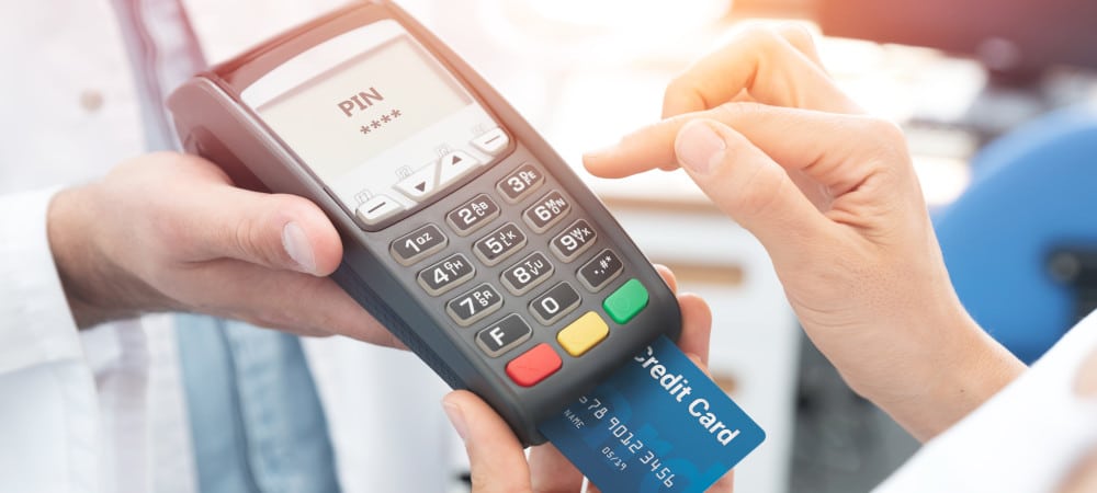 Consumidor pagando uma compra com cartão de crédito em uma "maquininha" portátil