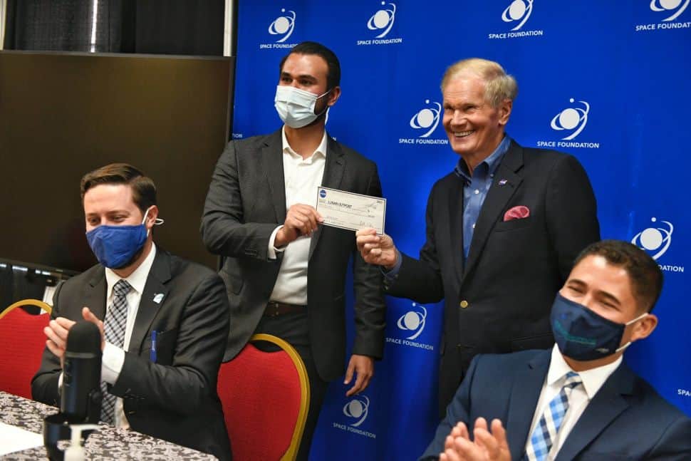 Foto mostra Bill Nelson, chefe da Nasa, entregando um cheque de dez centavos a Justin Cyrus, CEO da Lunar Outpost