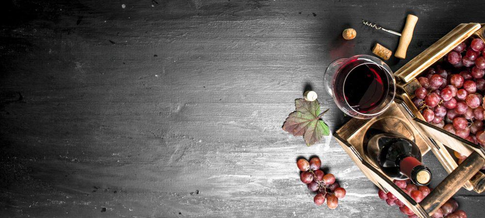 Taça e garrafa de vinho ao lado de uvas