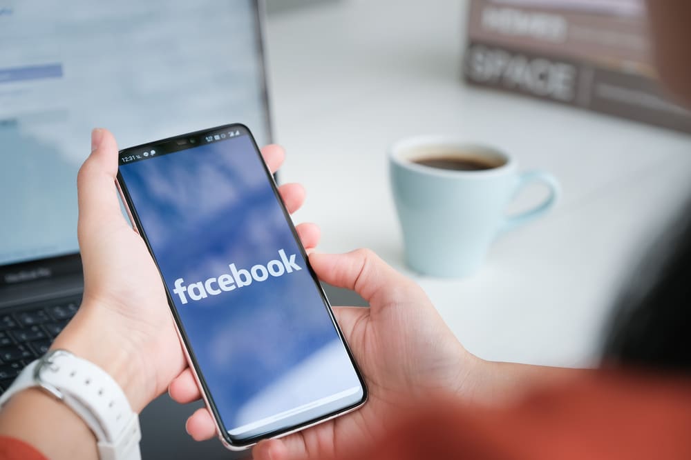 Uma mulher segura um celular com o aplicativo do Facebook na tela