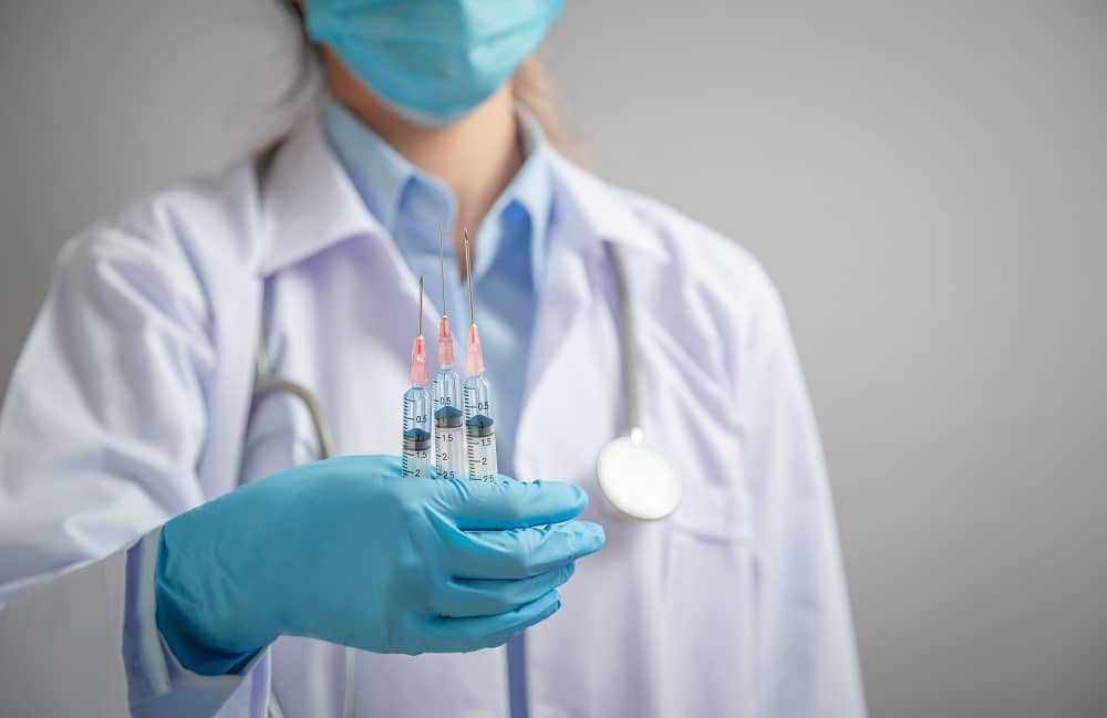 médica segura três doses de vacina contra Covid-19