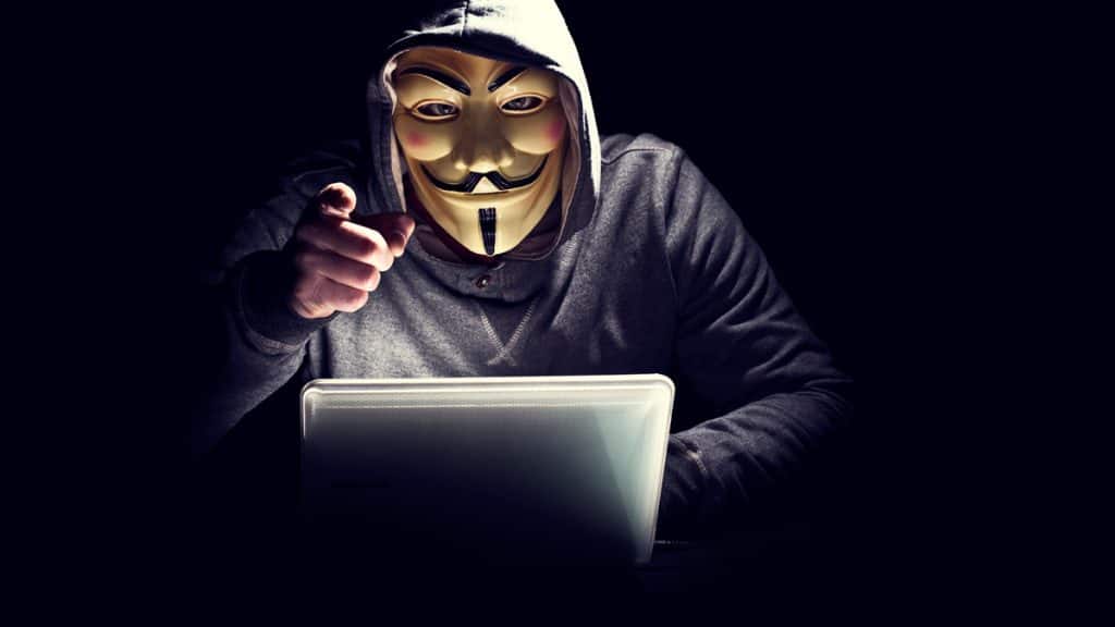 hacker com mascara do grupo anonymous apontando para você