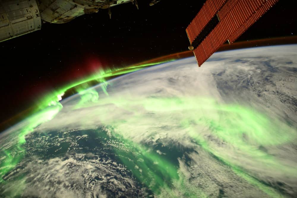 Imagem registrada pelo astronauta Thomas Pesquet mostra a aurora boreal, com a Terra vista em sua curva no espaço, com efeitos luminosos verdes brilhantes ocorrendo ao redor dela