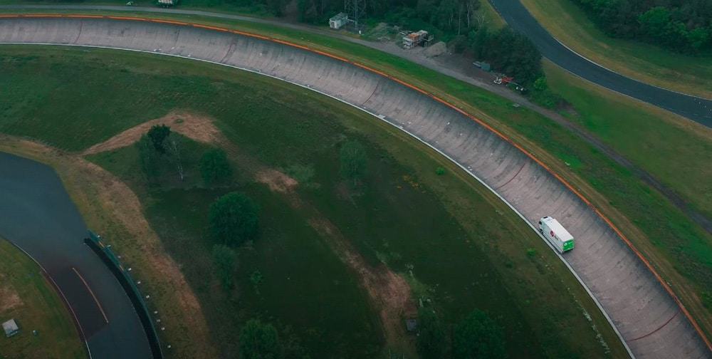 pista curva em meio a gramado com caminhão na parte inferior da estrada