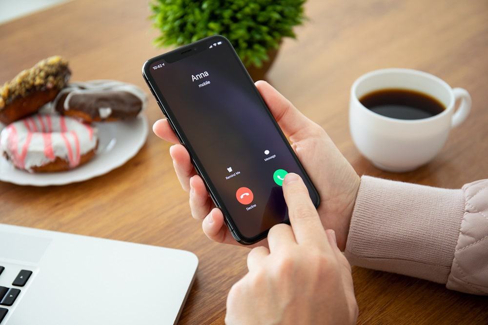 Imagem mostra uma mão masculina atendendo uma ligação no iPhone