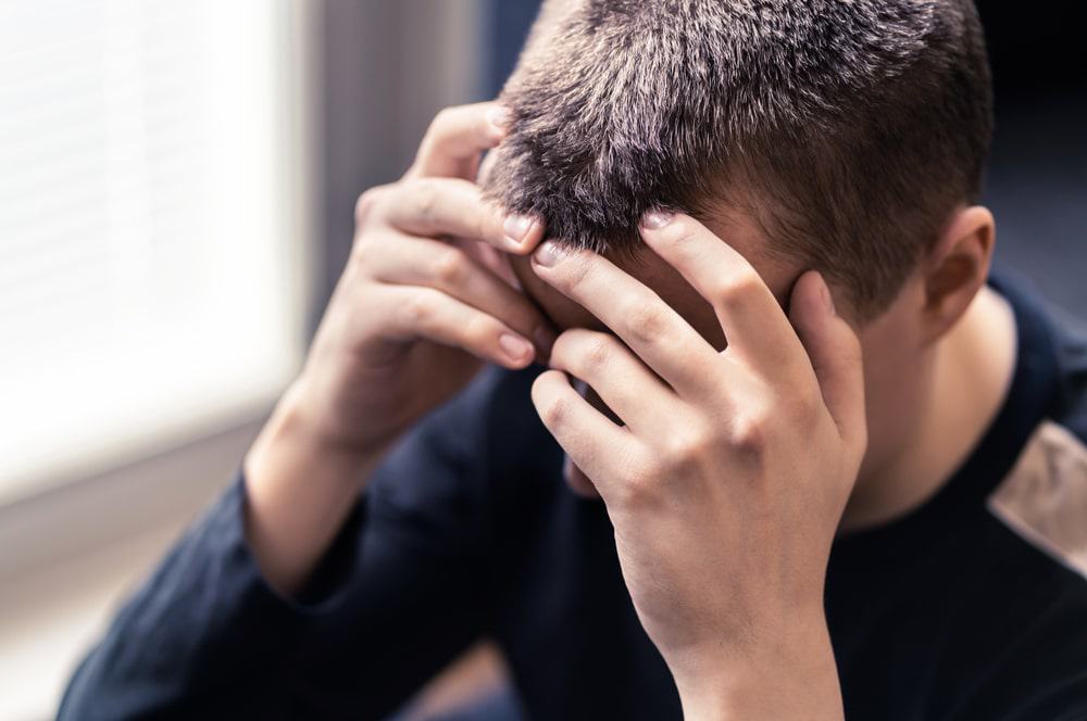 Imagem mostra um homem triste com as mãos na cabeça, simbolizando traumas. Estudo mostra que sonhos lúcidos podem ajudar pessoas a superar dificuldades psicológicoas