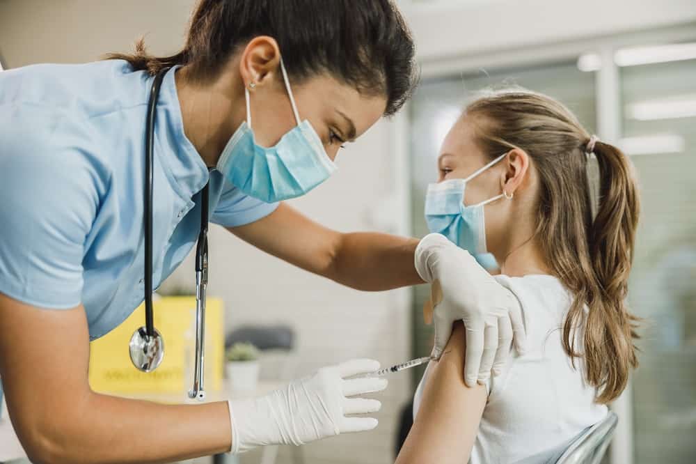 Profissional da saúde aplicando a vacina em adolescente