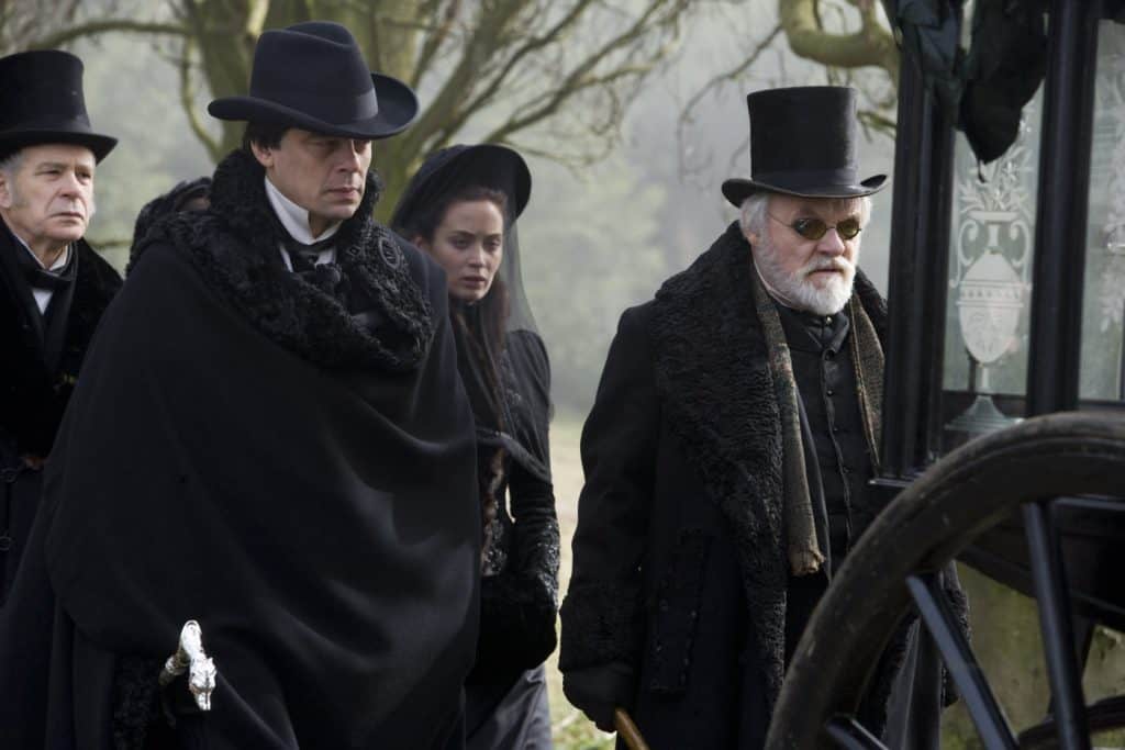 Benicio del Toro, Anthony Hopkins e Emily Blunt no funeral do responsável pelo financeiro de 'O Lobisomem'. Imagem: Universal Pictures/Divulgação