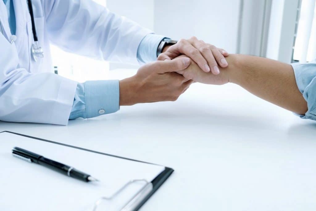 Médico com a mão sobre a mão do paciente