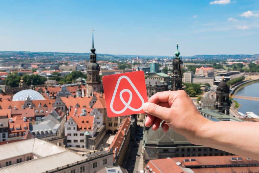Logo do Airbnb com paisagem de cidade ao fundo