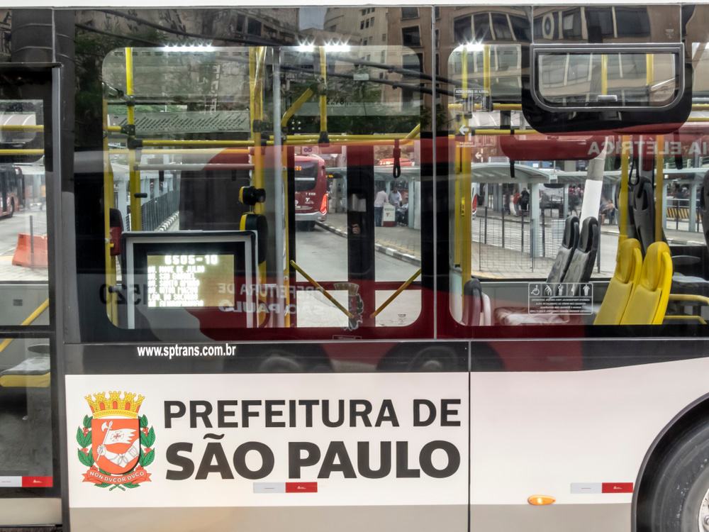 Imagem mostra a lateral externa de um ônibus da capital paulista, adesivado com os dizeres Prefeitura de São Paulo e o brasão da prefeitura.