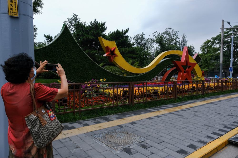 Imagem mostra cidadã chinesa fotografando atração que celebra o centenário do Partido Comunista Chinês, em julho de 2021.