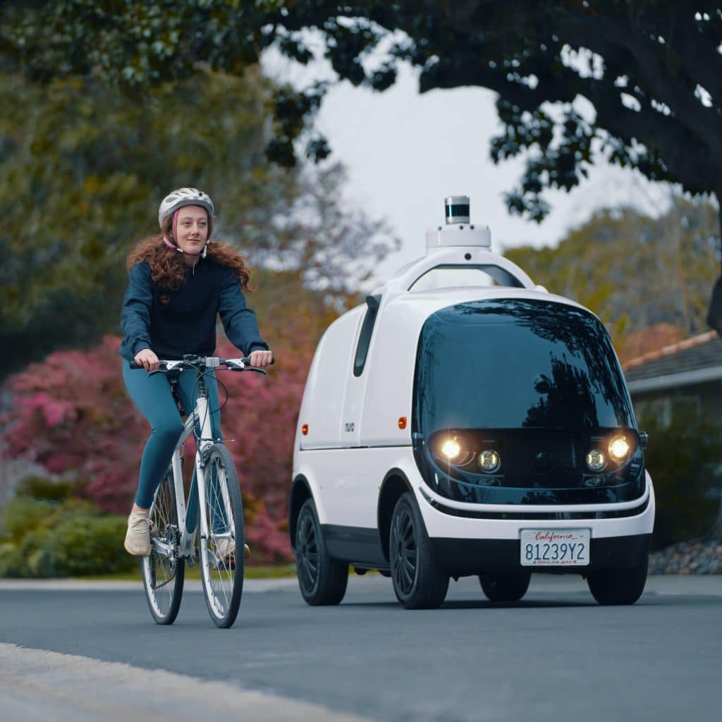 Imagem com o veículo autônomo e uma pessoa andando de bicicleta ao lado