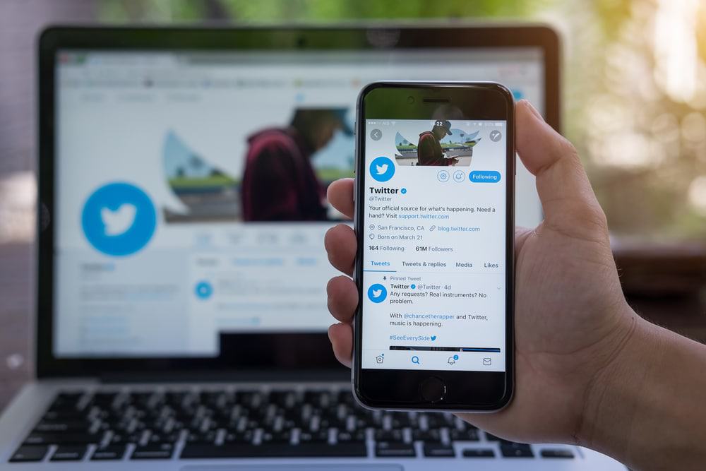 Pessoa segurando um iPhone com o aplicativo do Twitte exibido na tela. O Twitter é um serviço online de mídia social