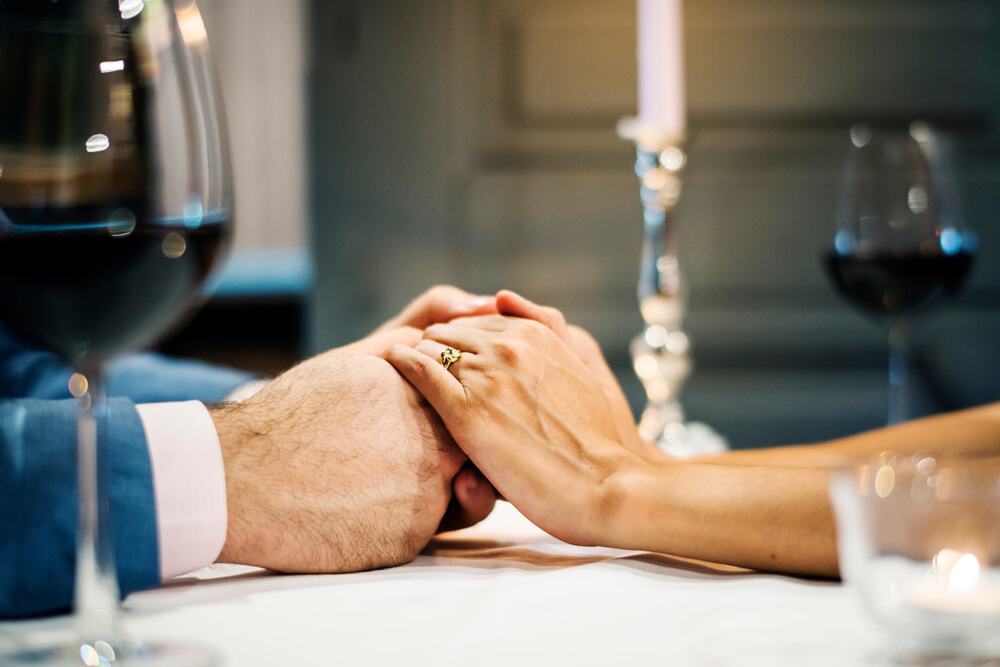 Casal de mãos dadas durante um jantar