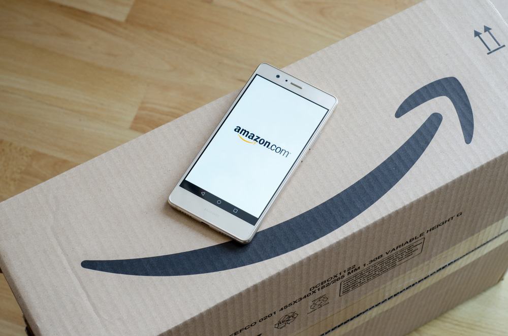 Logotipo da Amazon impresso em uma caixa de papelão e exibido na tela de um celular. Amazon.com, Inc., é uma empresa americana de comércio eletrônico e computação em nuvem.