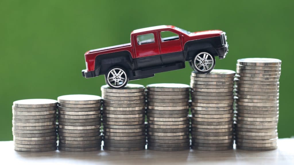 Carro subindo pilha de moedas, representando preços mais caros dos carros